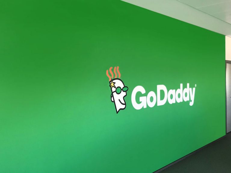 Green wall branded with big GoDaddy logo